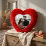 A personalized red heart fur cushion with a custom photo displayed as elegant home decor on a wooden cabinet by upahar18.