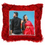 A close-up product shot of a personalized red square-shaped fur cushion with a couple's custom photo by upahar18.