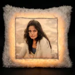 A dramatic dark room product shot of a glowing personalized white square LED fur cushion with an illuminated custom photo print from upahar18.
