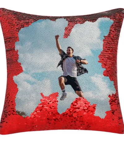 A close-up product shot of a personalized red square-shaped magic cushion partially revealing a joyful man jumping in the air by upahar18.