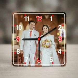 A square-shaped MDF clock from upahar18 standing on a wooden surface, displaying a printed custom photo of a newlywed bride and groom walking down a church aisle.