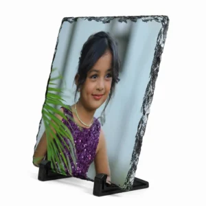 A sharp side angle perspective view of a square shape personalized rock stone frame by upahar18 on a white background. The print displays a smiling kid, while the sharp side angle perfectly highlights the heavy stone thickness, rustic side texture, and the low-profile black display stands.