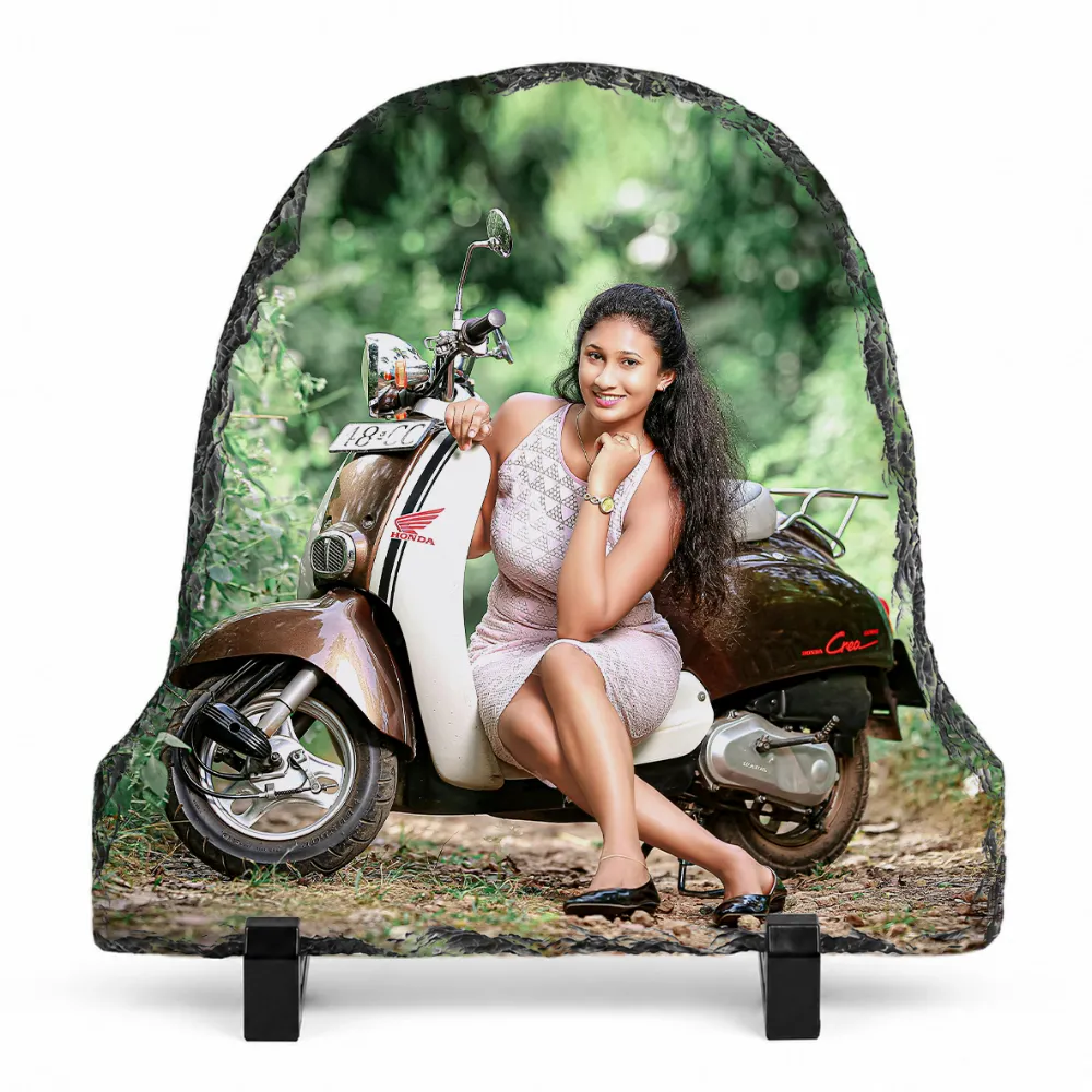 A bell shape natural rock stone frame from upahar18, featuring a personalized custom photo printed on it. The image shows a smiling woman in a light pink dress posing next to a vintage brown and cream scooter in a lush green outdoor setting, placed on two black plastic stands against a clean white background.