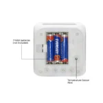 An overhead view showing the open back battery compartment at the bottom base of the white Upahar18 personalized photo printed led alarm clock. Inside the rectangular chamber, three red and blue EVEREADY brand AAA batteries are installed side-by-side. A line points to the compartment with the text '3*AAA batteries (not included)'. Below the compartment, four circular white rubber buttons are lined up horizontally, labeled 'TAP', 'UP', 'DOWN', 'SET', and 'AL'. A single black line points to a small pinhole on the right labeled 'Temperature Sensor Here'.