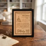 A custom engraved frame made of high-quality wooden finish MDF board by upahar18, showcasing a personalized birthday calendar of December 2024 with a heart mark on the date, a happy birthday wish, and a stylish black border.